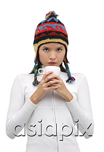 AsiaPix - Young woman wearing winter hat and holding mug of hot chocolate