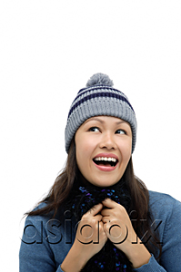 AsiaPix - Young woman wearing winter hat and scarf, smiling and looking up