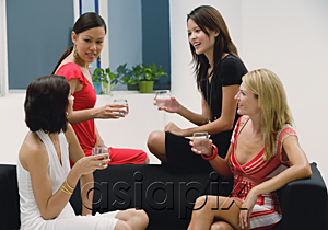 AsiaPix - Four women sitting on couch holding drinks and talking