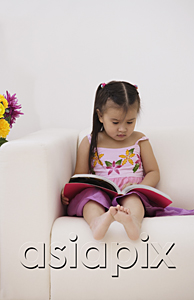 AsiaPix - A young girl sitting on the couch with a book