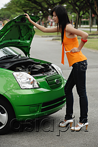 AsiaPix - A young woman looks under the hood of a car