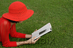 AsiaPix - A woman reads while lying on grass