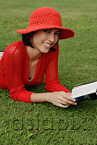 AsiaPix - A woman reads while lying on grass