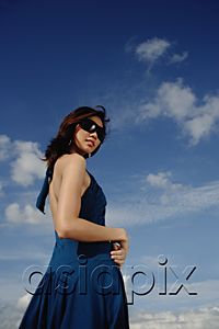 AsiaPix - A young woman with sunglasses stands with the sky in the background