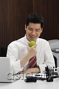 AsiaPix - A man eats an apple at his desk