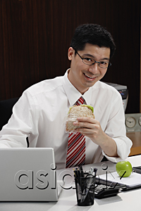 AsiaPix - A man eats lunch at his desk