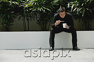 AsiaPix - A man eats with chopsticks while outdoors