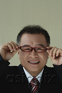 AsiaPix - A man smiles at the camera as he puts on his glasses