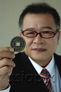 AsiaPix - A man holds out a Chinese coin