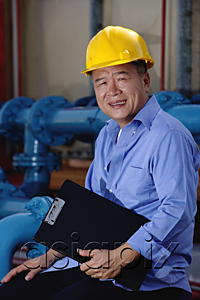AsiaPix - A man with a yellow helmet smiles at the camera as he works indoor