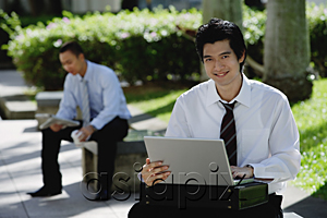 AsiaPix - A man uses his laptop in the park while he looks at the camera