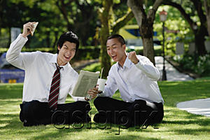 AsiaPix - Two men get excited as they read the newspaper in the park