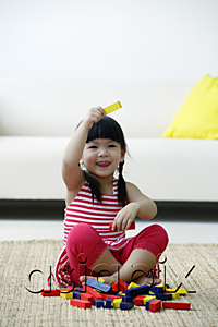 AsiaPix - A small girl plays with blocks on the floor