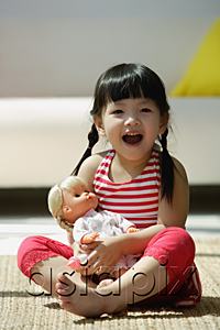 AsiaPix - A small girl plays with a doll as she looks at the camera