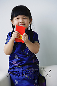 AsiaPix - A small girl holds a red packet as she looks at the camera