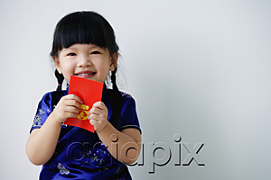 AsiaPix - A small girl holds a red packet as she looks at the camera