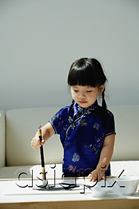 AsiaPix - A small girl in blue silk cheongsam writing Chinese calligraphy