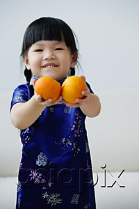 AsiaPix - A small girl holds out two mandarin oranges