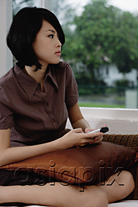 AsiaPix - A woman holds a cellphone as she looks out the window