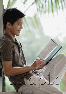 AsiaPix - A man smiles as he reads a book