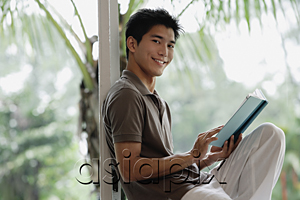 AsiaPix - A man smiles at the camera as he reads a book