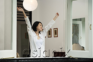 AsiaPix - A woman stretches out her arms in her house