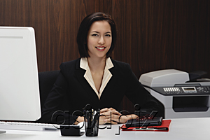 AsiaPix - A woman smiles at the camera while she works at her desk