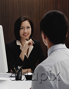 AsiaPix - A woman sits at her desk while she talks with a man