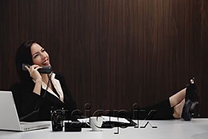 AsiaPix - A woman talks on the phone while she is at her desk