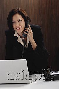 AsiaPix - A woman looks at the camera while she talks on the phone at work