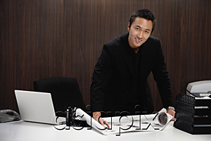 AsiaPix - A man smiles at the camera as he rolls out plans on his desk