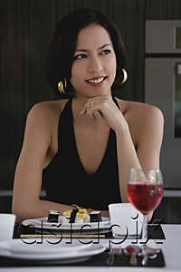 AsiaPix - A woman sits at a table with a plate of sushi and a glass of red wine