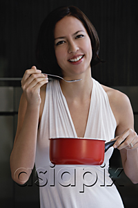 AsiaPix - A woman tastes her cooking as she looks at the camera
