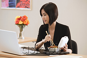 AsiaPix - A woman eats lunch at her desk while she works