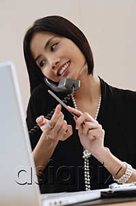 AsiaPix - A woman files her nails as she talks on the phone at work