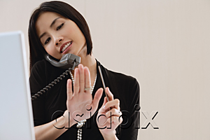 AsiaPix - A woman files her nails as she talks on the phone at work