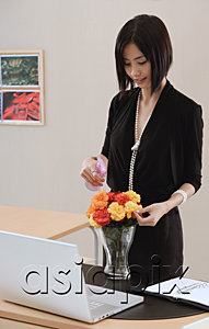 AsiaPix - A woman tends to a vase of flowers on her desk at work