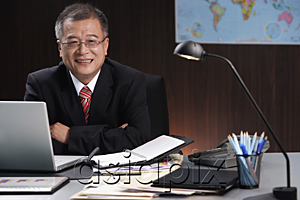 AsiaPix - A man smiles at the camera as he sits at his desk