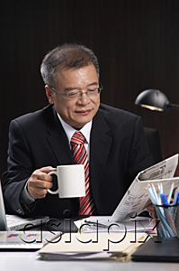 AsiaPix - A man having a drink while working at his desk