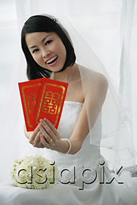 AsiaPix - A bride smiles at the camera and holds out two red envelopes
