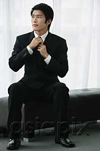 AsiaPix - A groom adjusts his tie as he sits down