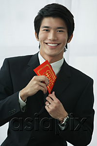 AsiaPix - A groom smiles at the camera as he puts a red envelope in his pocket
