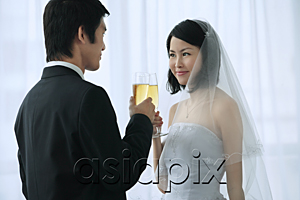 AsiaPix - A newlywed couple hold out their champagne glasses for a toast