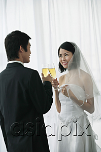 AsiaPix - A newlywed couple hold out their champagne glasses for a toast