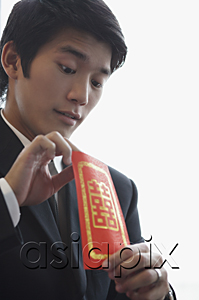 AsiaPix - A groom looks inside a red envelope