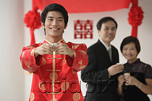 AsiaPix - A groom smiles at the camera as he holds out a cup