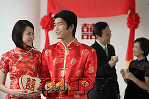 AsiaPix - A newlywed couple smile at each other as their family talk in the background