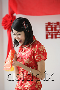AsiaPix - A bride looks excited as she looks inside a red envelope