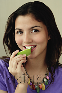 AsiaPix - A teenage girl looks at the camera as she eats a piece of fruit