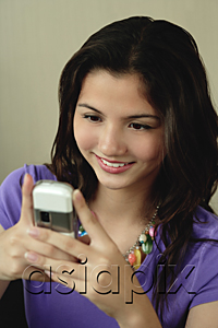 AsiaPix - A teenage girl smiles as she uses her cellphone